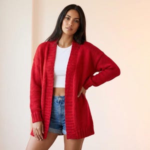 Puede incluir: Una mujer con un c&aacute;rdigan rojo largo y abierto. El c&aacute;rdigan se combina con un top corto blanco y pantalones cortos de mezclilla. El c&aacute;rdigan tiene mangas largas y dobladillo y pu&ntilde;os acanalados.