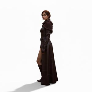 Puede incluir: Un abrigo largo de cuero burdeos oscuro con una abertura alta, mangas largas y un cintur&oacute;n. El abrigo se combina con botas a juego y un chal de punto. La modelo est&aacute; sobre un fondo blanco.