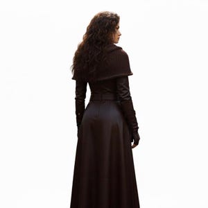 Puede incluir: Abrigo largo de cuero marr&oacute;n oscuro con cintur&oacute;n y guantes a juego. El abrigo tiene un cuello alto y una falda larga. Se lleva un chal de punto marr&oacute;n sobre los hombros. La persona est&aacute; de espaldas a la c&aacute;mara.