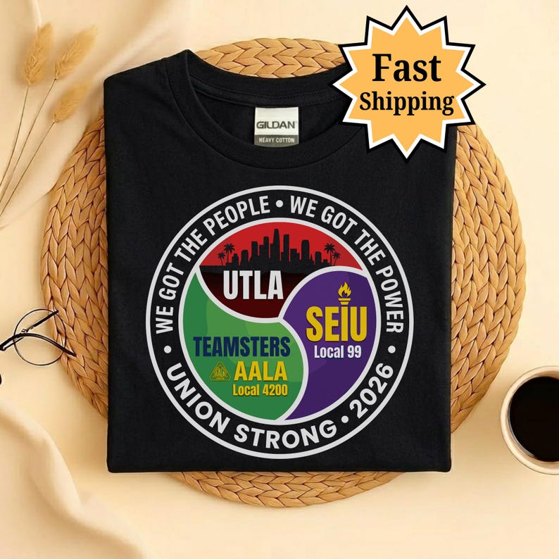 May include: Black t-shirt with a circular graphic featuring the text "WE GOT THE PEOPLE WE GOT THE POWER" and the words "UTLA", "TEAMSTERS AALA Local 4200", and "SEIU Local 99". The shirt also has the text "UNION STRONG 2026".