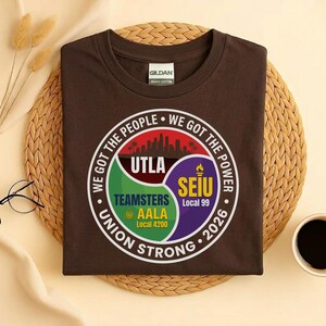 May include: A brown t-shirt with a circular graphic featuring the text "WE GOT THE PEOPLE WE GOT THE POWER" and "UNION STRONG 2026". The graphic includes the logos for UTLA, Teamsters AALA Local 4200, and SEIU Local 99.