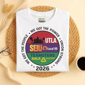 May include: White Gildan heavy cotton t-shirt with a circular graphic. The graphic includes text that reads "WE GOT THE POWER", "UTLA", "SEIU Local 99", "TEAMSTERS AALA Local 2010", and "2026". The design features a skyline and a fist.