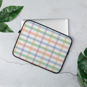May include: A laptop sleeve with a colorful plaid pattern in shades of pink, blue, green, and orange. The sleeve is made of a soft, durable material and has a zipper closure.