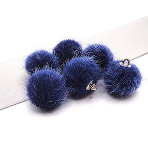 Könnte beinhalten: Eine Ansammlung von sechs runden, tiefblauen, flauschigen Pompons, die jeweils mit einer kleinen silberfarbenen Metallöse an der Oberseite zur Befestigung versehen sind. Die Pompons sind in einer Gruppe angeordnet und zeigen ihre weiche Textur.