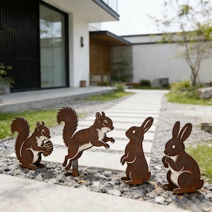 May include: Four rusty brown metal yard art pieces depicting a squirrel with a pinecone, a jumping squirrel, and two rabbits. The squirrel and rabbit silhouettes are placed on a gravel path in front of a house.
