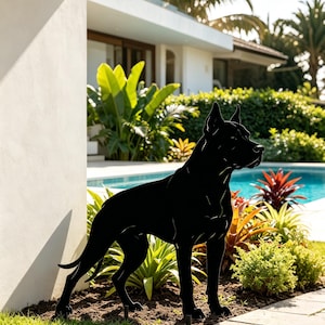 Può includere: Una sagoma in metallo nero massiccio di un cane in piedi con orecchie a punta e corporatura muscolosa, progettata come decorazione da giardino. La figura piatta e opaca presenta un contorno netto di un canino in un profilo laterale.