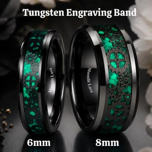 Könnte beinhalten: Zwei schwarze Wolframringe, 6 mm und 8 mm breit, mit einer zentralen Einlage aus grün leuchtendem Material und einem schwarzen Zahnradmuster. Die Innenseite ist mit Moonlit Love graviert. Der Text Tungsten Engraving Band ist zu sehen.