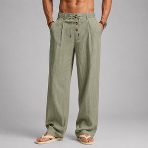 Könnte beinhalten: Salbeigrüne Hose mit hoher Taille, elastischem Bund, Kordelzug und einer vertikalen Reihe aus drei dunkelbraunen Knöpfen. Diese Hose mit weitem Bein verfügt über zwei Seitentaschen und eine lockere, gerade Passform.