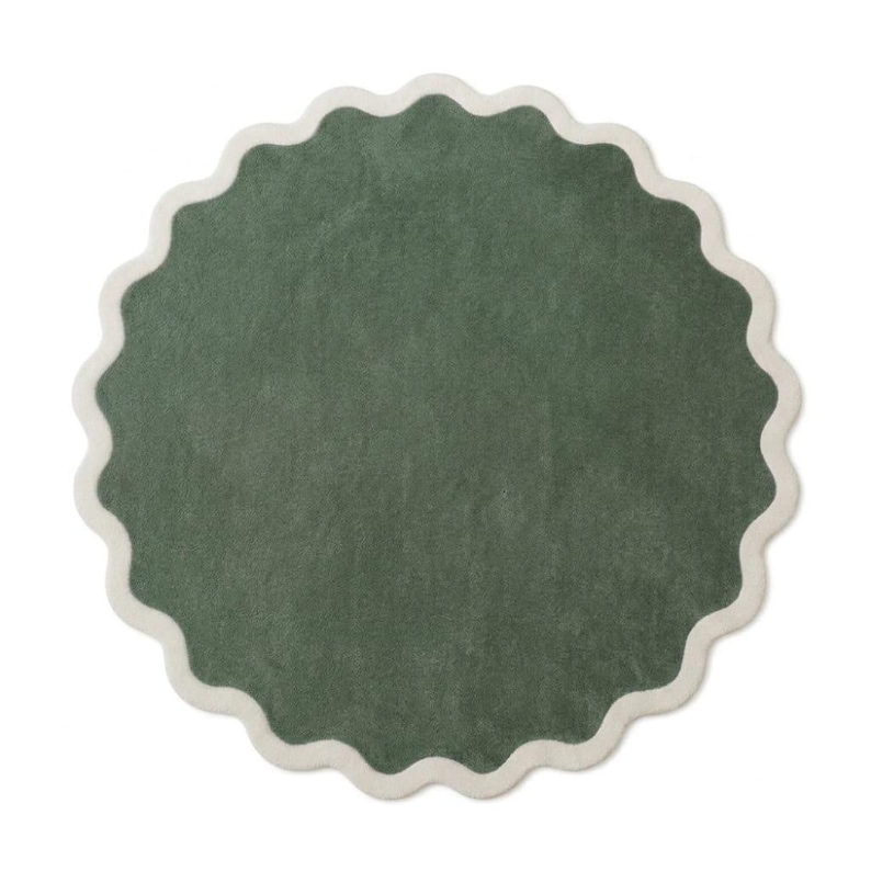 May include: A circular rug featuring a deep forest green center with a textured, soft-looking surface. The rug is framed by a distinct, wide scalloped border in a contrasting off-white or cream color, creating a wavy edge around the entire perimeter.