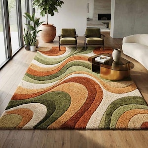 Könnte beinhalten: Ein rechteckiger Teppich mit Hochflor-Textur und einem sich wiederholenden Muster aus wellenförmigen, geschwungenen Bändern in den Farben gebranntes Orange, Olivgrün, Salbei und Creme. Der Teppich liegt auf einem Holzboden.
