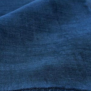 May include: A deep navy blue textile fabric with a soft, dense, and uniform pile surface. The material is folded over, creating a gentle curve that highlights the rich, dark blue color and the subtle, velvety texture of the fabric's fibers.