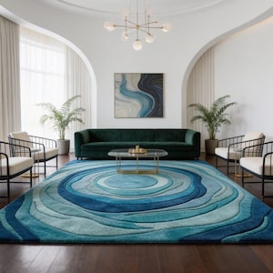Könnte beinhalten: Ein großer rechteckiger Teppich mit einem konzentrischen Kreismuster in verschiedenen Blautönen, von tiefem Marineblau bis zu hellem Türkis, mit einem strukturierten, geschichteten Design, das eine Tiefenwirkung erzeugt.