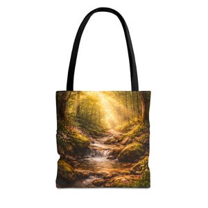 May include: Tote bag featuring a vibrant forest scene with a stream flowing through a sunlit path. The bag has a black handle and showcases a detailed landscape with lush greenery, rocks, and a bright, golden light filtering through the trees.