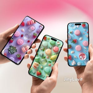May include: Three smartphones with colorful screens featuring macarons, strawberries, and other decorative elements. The phones are held in hands against a pink background. The screens have different color schemes, including purple, green, and blue.