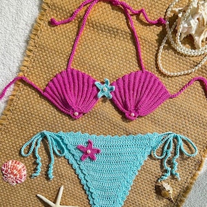 May include: A set of three ceramic mugs with a speckled, cream-coloured glaze. Each mug features a different hand-painted design: a blue and green leaf, a yellow flower, and a red berry. The mugs have a simple, modern design.