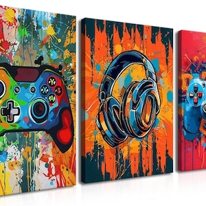 May include: A set of three colorful canvas prints featuring gaming themes. The prints showcase a vibrant controller, headphones, and another controller, all with a splash art style. The color palette includes blues, greens, yellows, and reds, perfect for a game room.