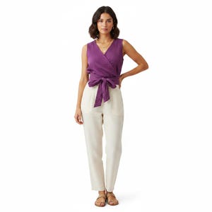 May include: A sleeveless purple wrap top with a V-neckline and a tie-waist detail, paired with off-white trousers featuring side pockets. The ensemble consists of a solid-colored top and light-colored pants, creating a two-piece outfit combination.
