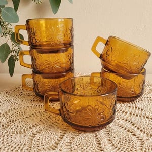6er-Set stapelbarer, umweltfreundlicher, bernsteinfarbener Gläser von Vereco France – Reliefdekor mit Gänseblümchen – Vintage-Retro-Chic der 70er Jahre