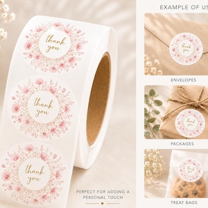 May include: A roll of circular white stickers featuring a pink floral wreath design and the text thank you in gold script. The stickers are shown applied to a brown envelope, a wrapped package with twine, and a clear treat bag with a cookie.