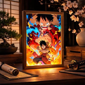 Può includere: Un'opera d'arte incorniciata e illuminata con una vivace illustrazione anime. L'immagine raffigura un personaggio con un cappello di paglia, su uno sfondo di rossi, arancioni e blu infuocati. La cornice è in legno e l'estetica generale è un mix di stili moderni e tradizionali.