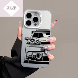May include: Clear phone case with a black and white car graphic. The case has a Case Pro label and a Zeus Accessories logo in the upper left corner. The car design features headlights, a grill, and exhaust pipes.