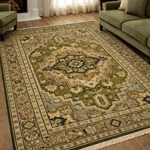 May include: A rectangular area rug with an intricate, traditional design. The rug features a central medallion in shades of green, blue, and beige, surrounded by a detailed border. The rug has a fringe on the short ends and is placed on a hardwood floor.