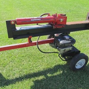 May include: A red and black Yard Machines log splitter with a gasoline engine. The splitter has a red hydraulic cylinder and a black splitting wedge. It is mounted on a two-wheel chassis and is designed for splitting firewood.