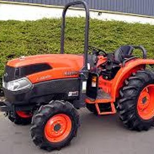 May include: An orange and black tractor with large, black tyres and orange rims. The tractor has a black roll bar and a black seat. It is parked on a paved surface in front of a green hedge.
