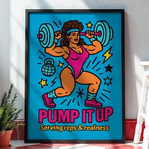 May include: A framed poster with a cartoon illustration of a muscular person lifting a barbell. The person is wearing a pink leotard and headband. The poster has the text "PUMP IT UP" and "Serving reps & realness" in bright colors against a blue background.
