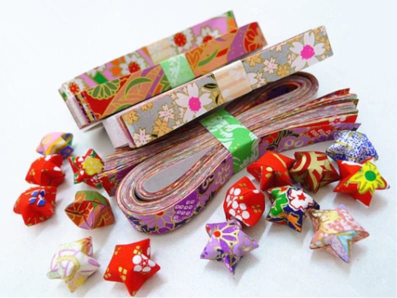 May include: Assortment of colorful origami paper strips with floral patterns, and a collection of finished origami stars in various colors and patterns.