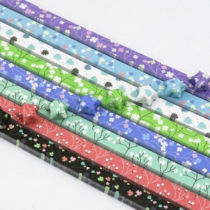 May include: Assortment of colourful origami paper strips with floral patterns. The strips are arranged in a fan shape with origami stars made from the paper.