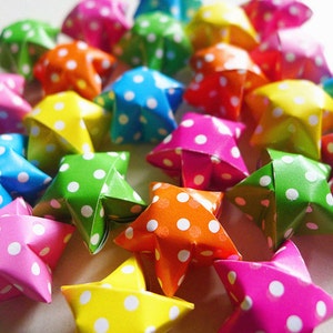 Peut inclure: Une collection d'étoiles en origami colorées avec des pois blancs. Les étoiles sont en papier et sont pliées en forme tridimensionnelle.