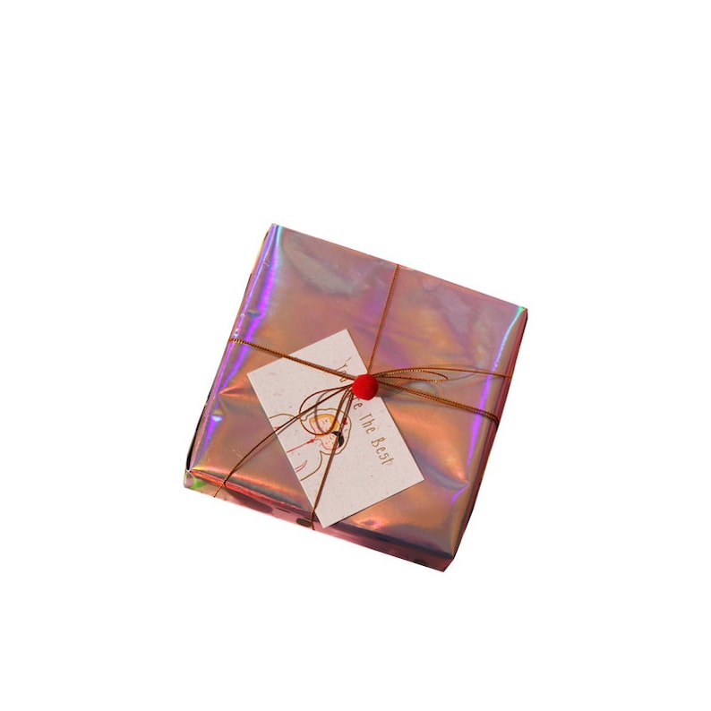 May include: A small gift box wrapped in iridescent pink holographic paper with a brown ribbon and a red pom-pom tied to the tag. The tag is white with black ink and says "You are the Best!"