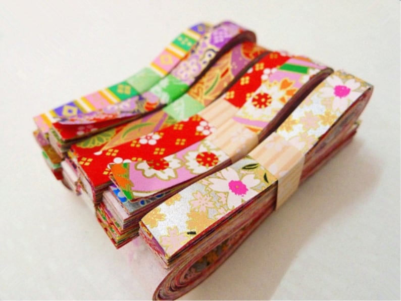 May include: A stack of colorful washi tape rolls with floral and geometric patterns. The tape is made of Japanese paper and is perfect for adding a touch of whimsy to crafts, gifts, and home decor.