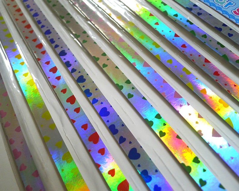 May include: Assortment of iridescent holographic washi tape with a heart pattern in various colors, including pink, blue, green, and red.