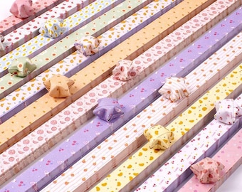 May include: A set of colorful paper strips with different patterns, each with a folded origami star on top. The stars are in various colors, including pink, yellow, blue, and green. The strips are arranged in a staggered pattern, creating a visually appealing display.