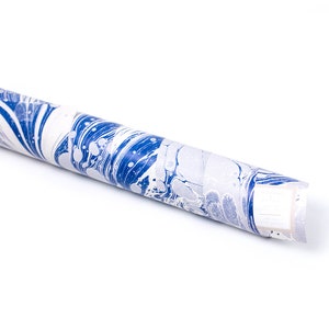 Puede incluir: Un rollo de papel de regalo marmoleado azul y blanco. El papel tiene un patr&oacute;n de remolino con remolinos y puntos azules y blancos.