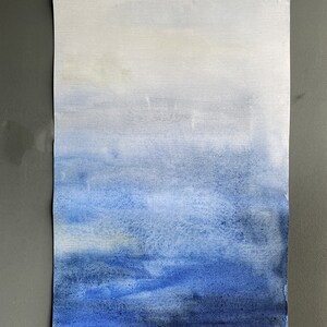 May include: A watercolour painting of a blue sky with white clouds. The sky is painted in shades of blue, from light blue at the top to dark blue at the bottom. The clouds are white and fluffy.