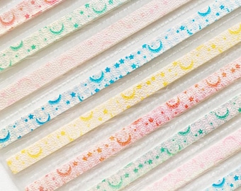 May include: A set of eight decorative washi tapes with a moon and star pattern. The tapes are in various pastel colors, including pink, blue, yellow, and green.