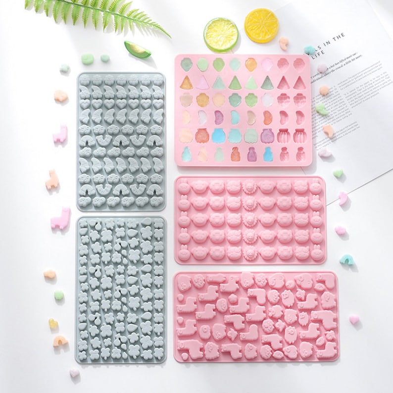 May include: Set of six silicone candy moulds with various designs. The moulds are pink and grey and feature different shapes, including animals, flowers, and geometric shapes.