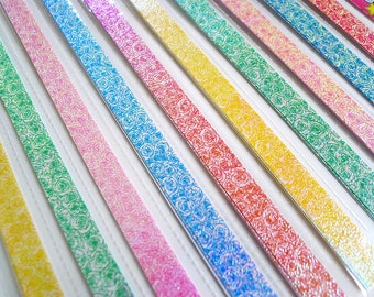May include: Assortment of colorful paper strips with a rose pattern. The strips are iridescent and have a glittery finish.