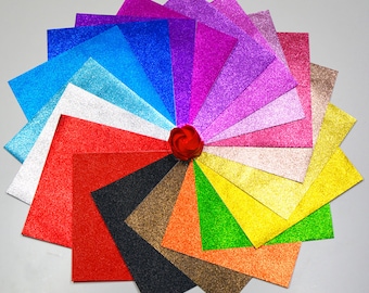 May include: A fan of 16 glitter paper sheets in various colours, including red, blue, green, yellow, purple, and pink. The sheets are arranged in a circle with a red rose in the centre.