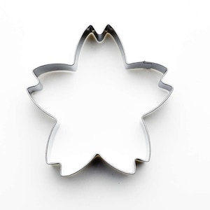 May include: A silver metal cookie cutter shaped like a flower with five petals.