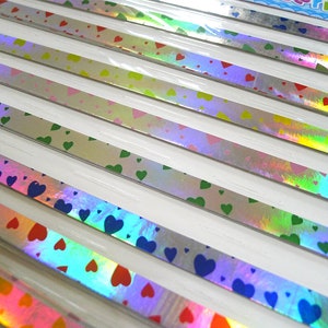 May include: Assortment of iridescent holographic washi tape with heart patterns in various colors, including blue, green, pink, and red.