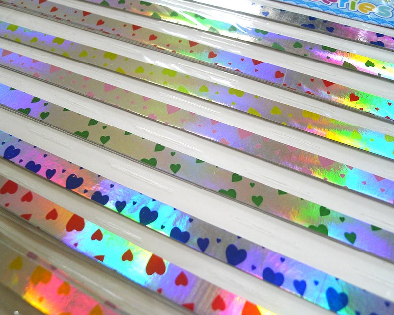 May include: Assortment of iridescent holographic washi tape with heart patterns in various colors, including blue, green, pink, and red.