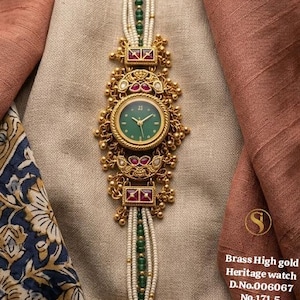 May include: A gold-toned heritage watch with a green face and white beaded strap. The watch features intricate detailing with red and green accents. The text on the image reads "Brass High gold Heritage watch D.No.006067 No.171.5".