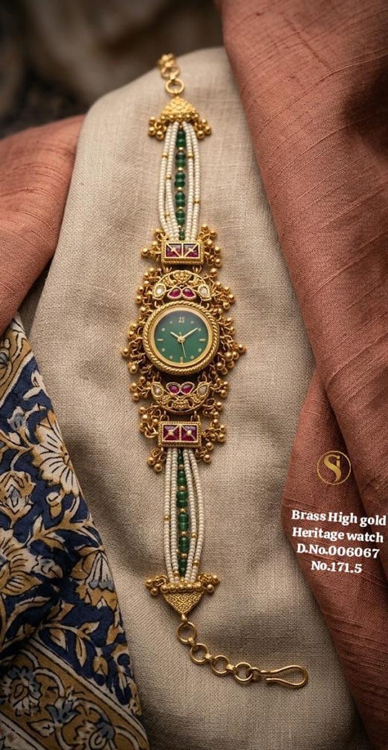 May include: A gold-toned heritage watch with a green face and white beaded strap. The watch features intricate detailing with red and green accents. The text on the image reads "Brass High gold Heritage watch D.No.006067 No.171.5".