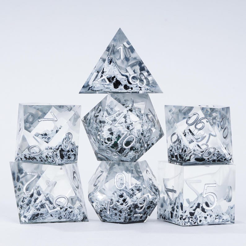 Peut inclure: Un ensemble de sept d&eacute;s poly&eacute;driques de diff&eacute;rentes formes, dont un d4, d6, d8, d10, d12, d20 et un d&eacute; de pourcentage. Les d&eacute;s sont transparents avec un effet marbr&eacute; argent&eacute; et noir et des chiffres argent&eacute;s.