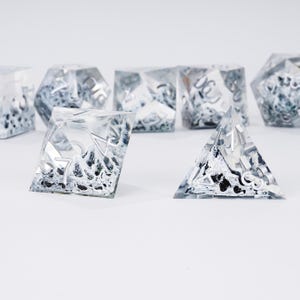 Peut inclure: Ensemble de d&eacute;s en r&eacute;sine transparente avec des chiffres argent&eacute;s et un int&eacute;rieur textur&eacute; noir et blanc. Les d&eacute;s sont de formes g&eacute;om&eacute;triques vari&eacute;es, comme une pyramide et un cube, pour les jeux de r&ocirc;le.