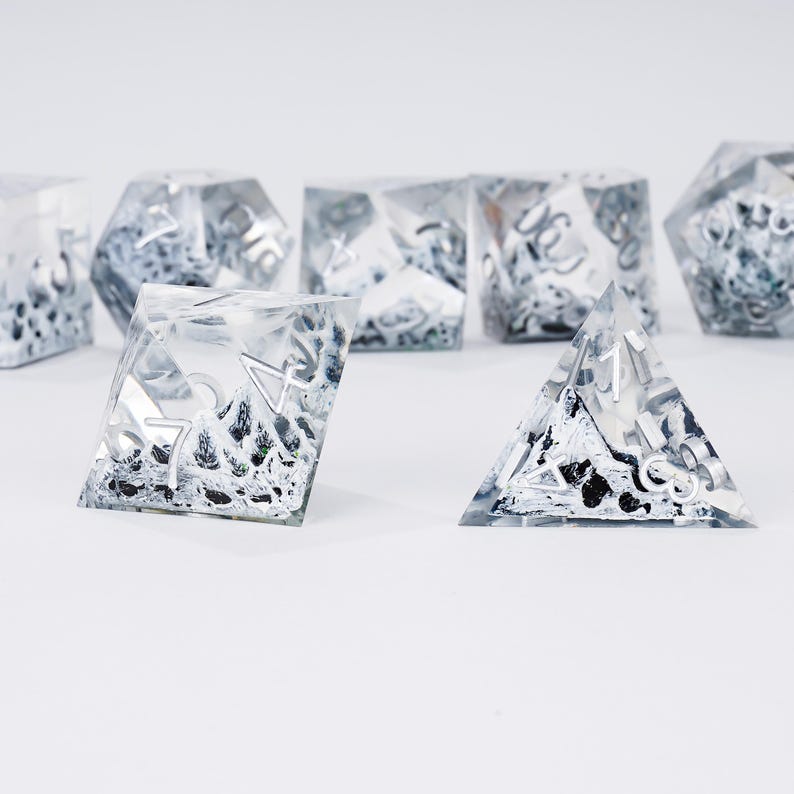 Peut inclure: Ensemble de d&eacute;s en r&eacute;sine transparente avec des chiffres argent&eacute;s et un int&eacute;rieur textur&eacute; noir et blanc. Les d&eacute;s sont de formes g&eacute;om&eacute;triques vari&eacute;es, comme une pyramide et un cube, pour les jeux de r&ocirc;le.